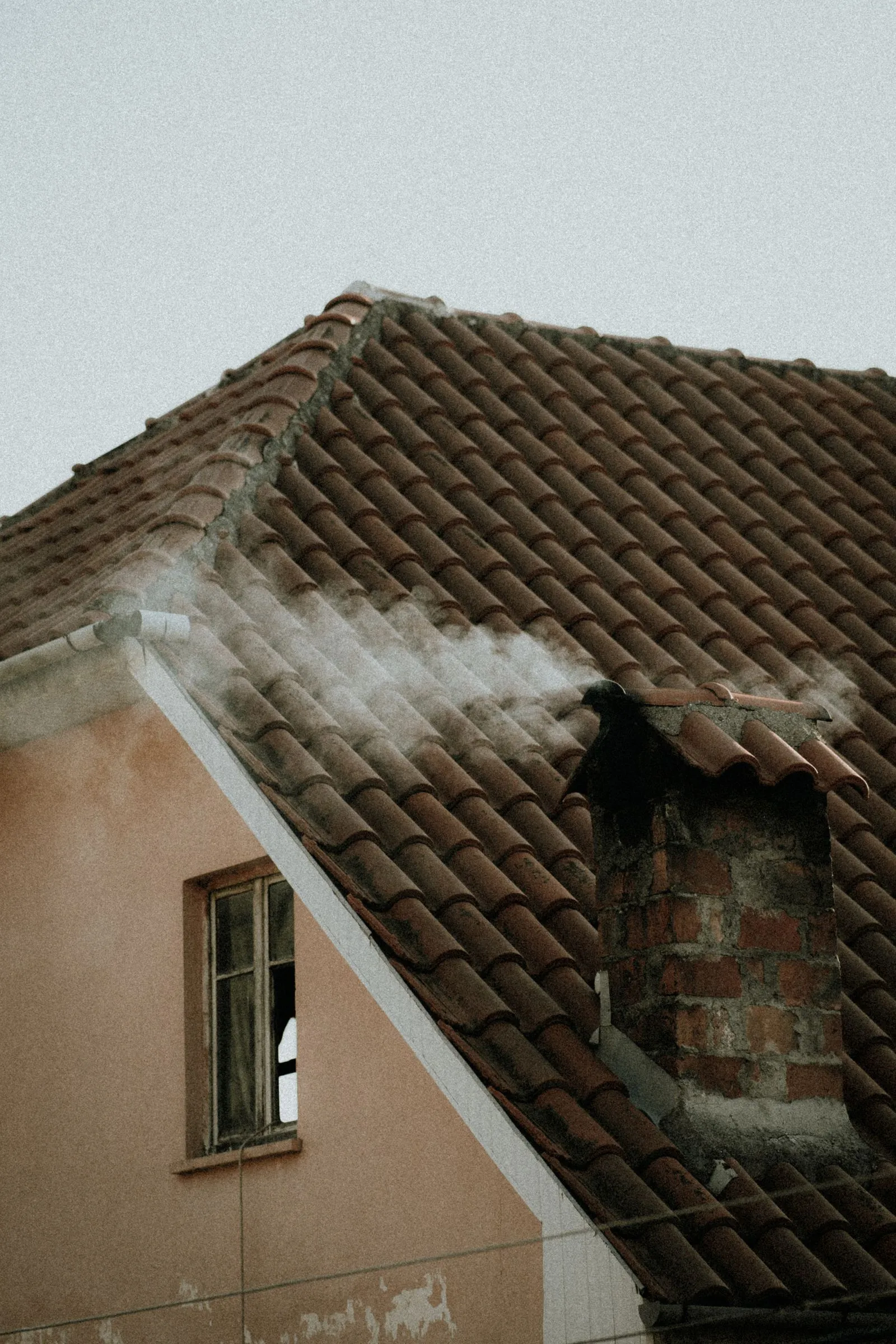 Tašková střecha s kouřícím komínem